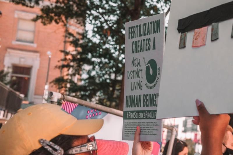 Man holding a sign promoting life at conception