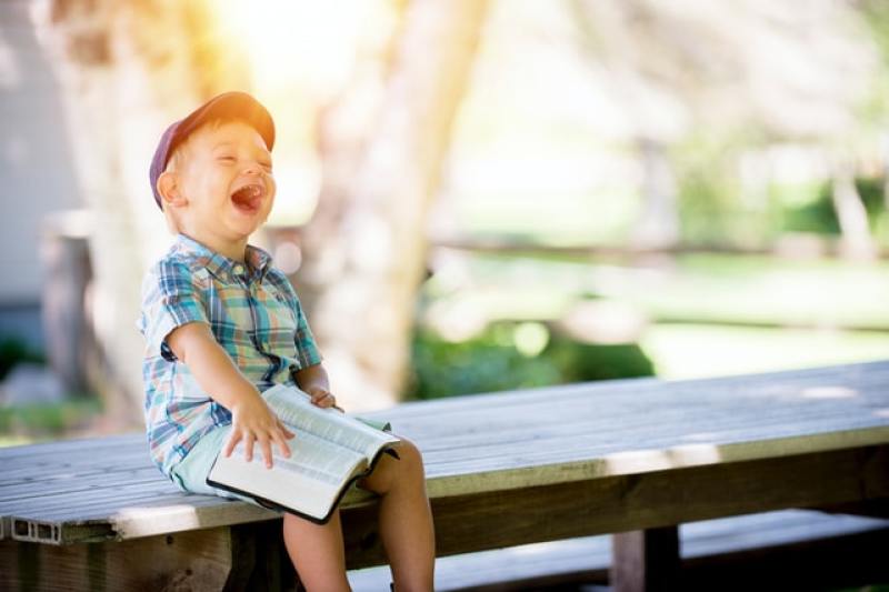Child reading a Bible laughing happy life