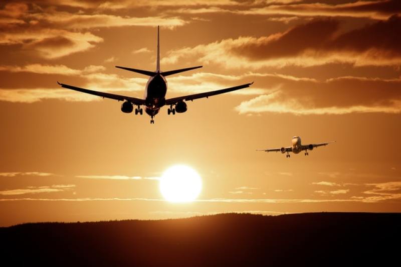 silhouettes of planes in flight towards the sunset